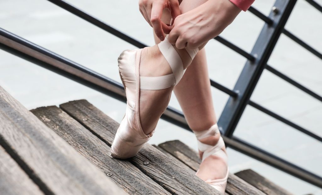 A ballet dancer fastening her BLOCH Pointe Shoe ribbons outside of the studio